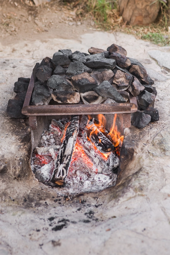 Pachamanca cooking fire pit with hot stones and burning wood in Peru